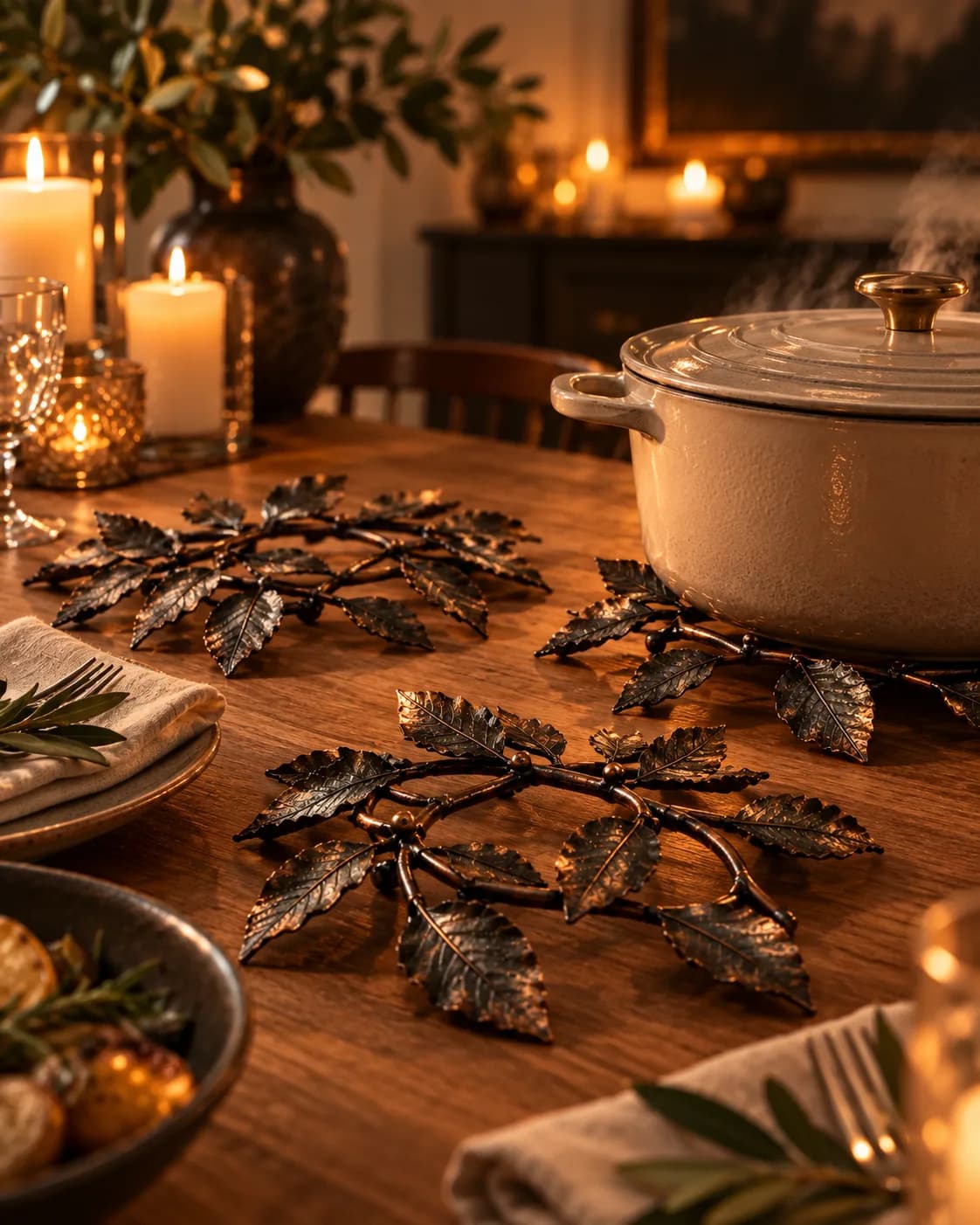 Three Hlíf leaf-shaped trivets on a dining table; one under a ceramic pot.